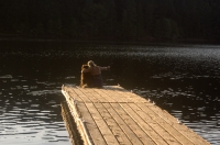 Sugar Pine Reservoir, Foresthill, California Woman and her dog sitting on the end of a dock, Sugar Pine Reservoir, near Foresthill, California