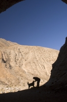 Death Valley National Park, California  Man & dog at the entrance to a cave in Cottonwood Canyon, Death Valley National Park, California